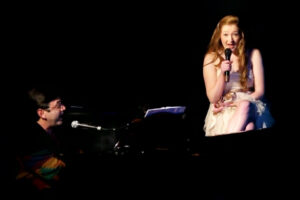 A woman is singing on stage with a man.
