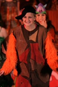 A woman in costume and orange feathers on stage.