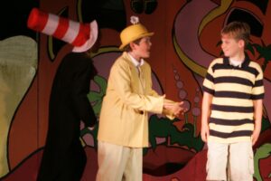 A man in yellow hat and striped shirt on stage.