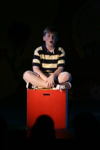 A boy sitting on top of a red box.