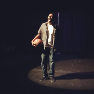 A man holding a basketball on top of a stage.